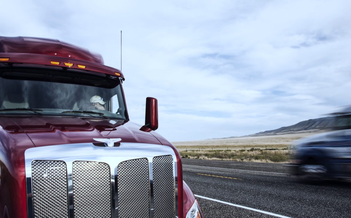 Chrome grille of a maroon semi truck on a desert highway